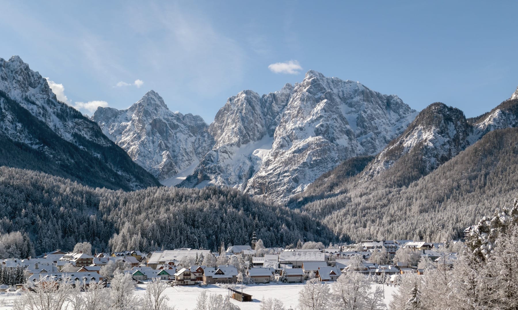 Kranjska Gora village below jagged snow-covered Julian Alps peaks on a clear winter day