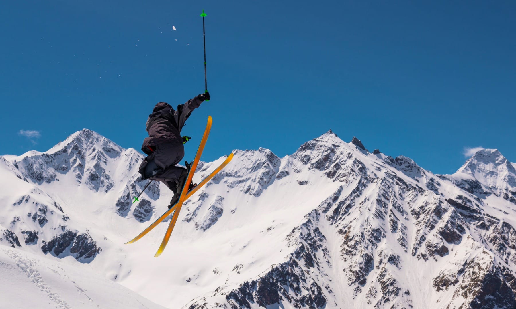 Freestyle skier jumping mid-air against a backdrop of snowy Julian Alps peaks
