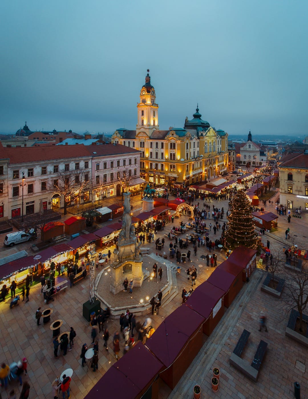 Aerial dusk view of Maribor's main square Christmas market with a large lit tree and crowds