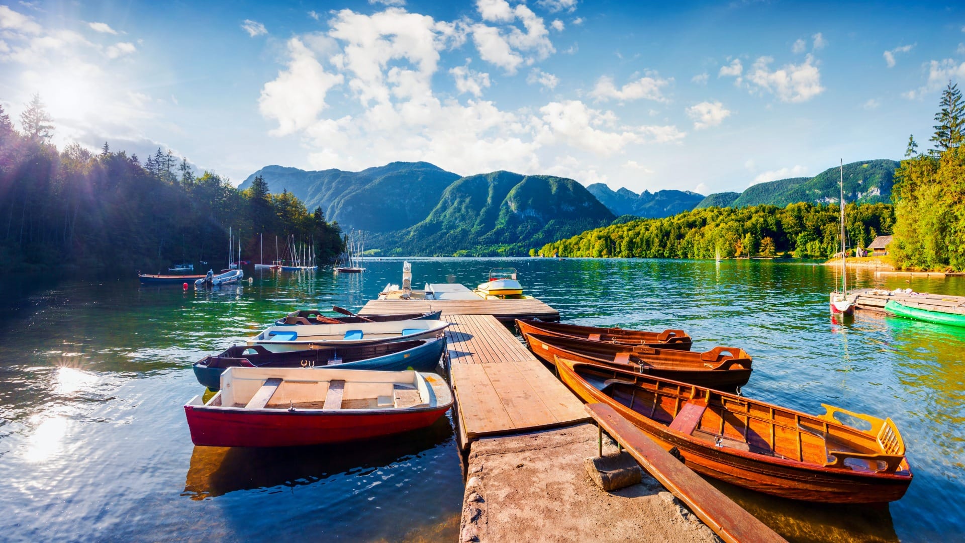Wooden boat pier with rowing boats on Lake Bohinj, mountains behind