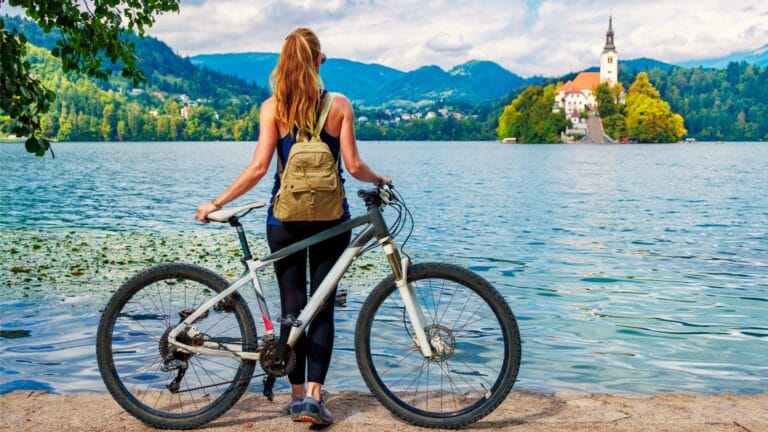 Cyclist with mountain bike looking out over Lake Bled toward the island church