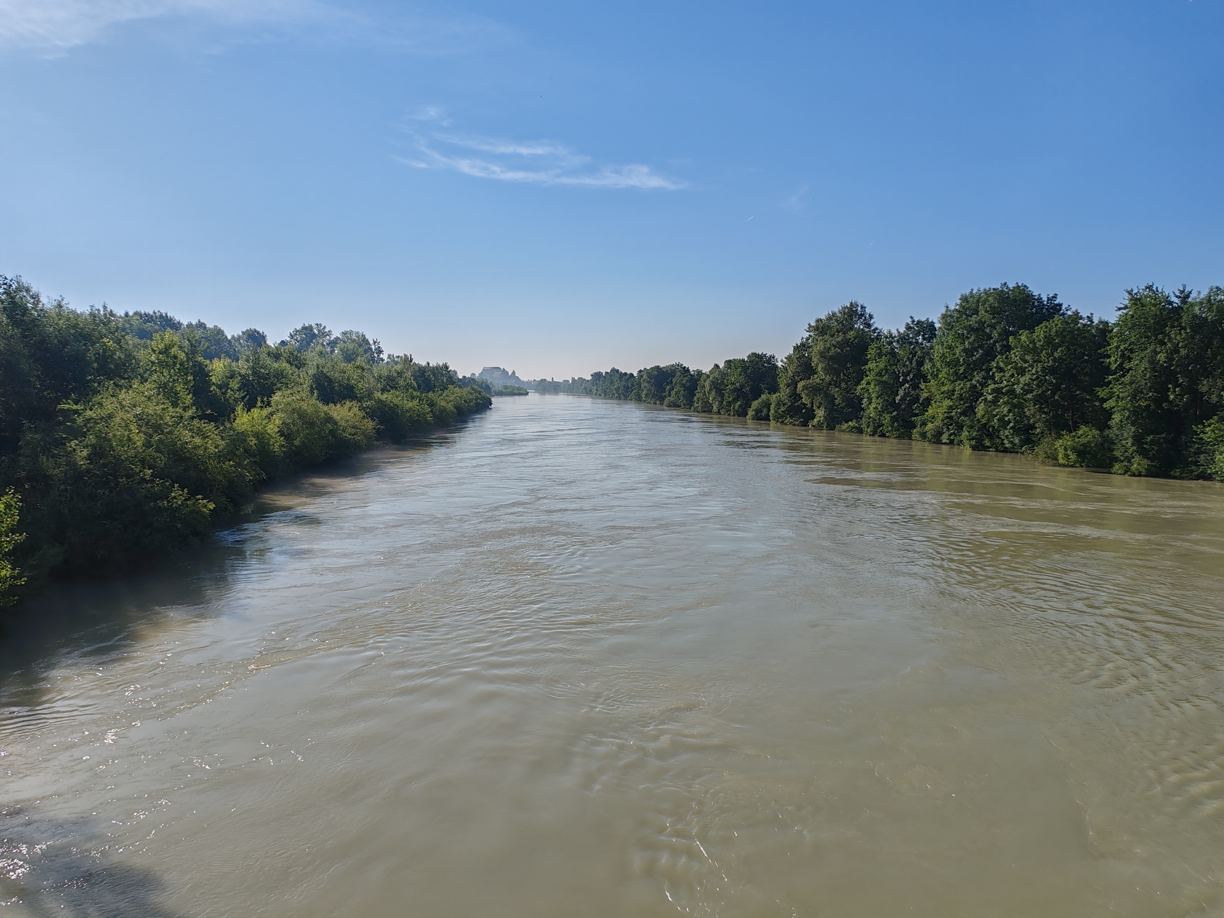 The wide, fast Drava river seen from the bridge at Hajdina, wooded banks on both sides and Ptuj Castle faint on the horizon
