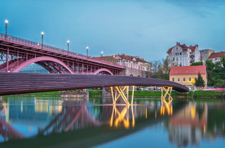 Maribors Old Bridge and the new wooden footbridge over the Drava at dusk, Lent embankment behind