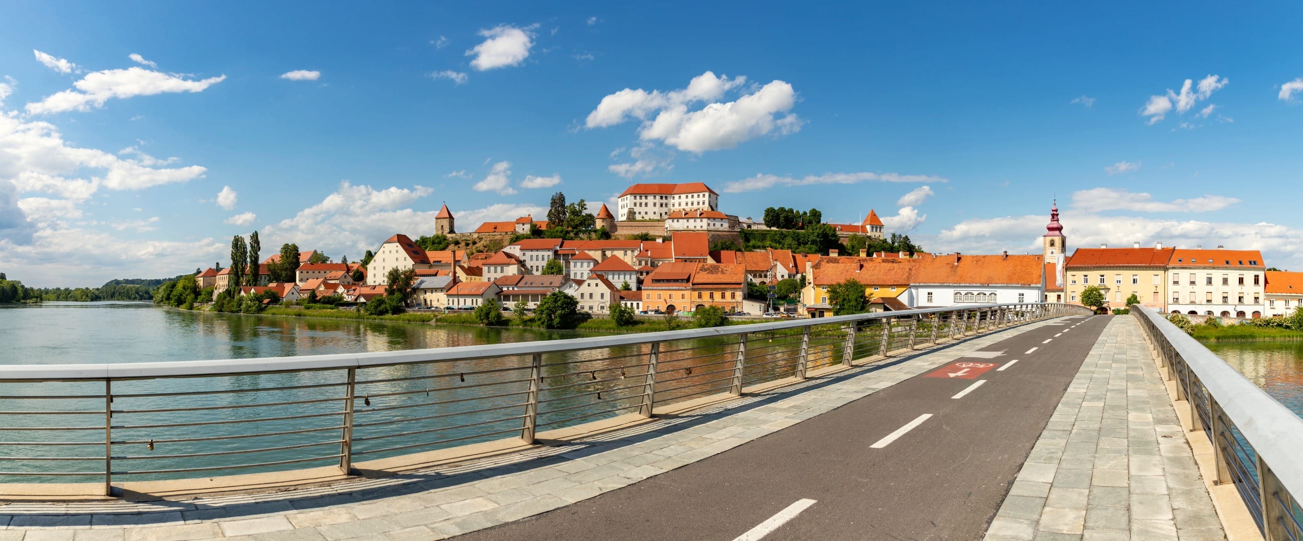 Panorama of Ptuj old town and castle across the Drava, seen from the cycle path on the town bridge