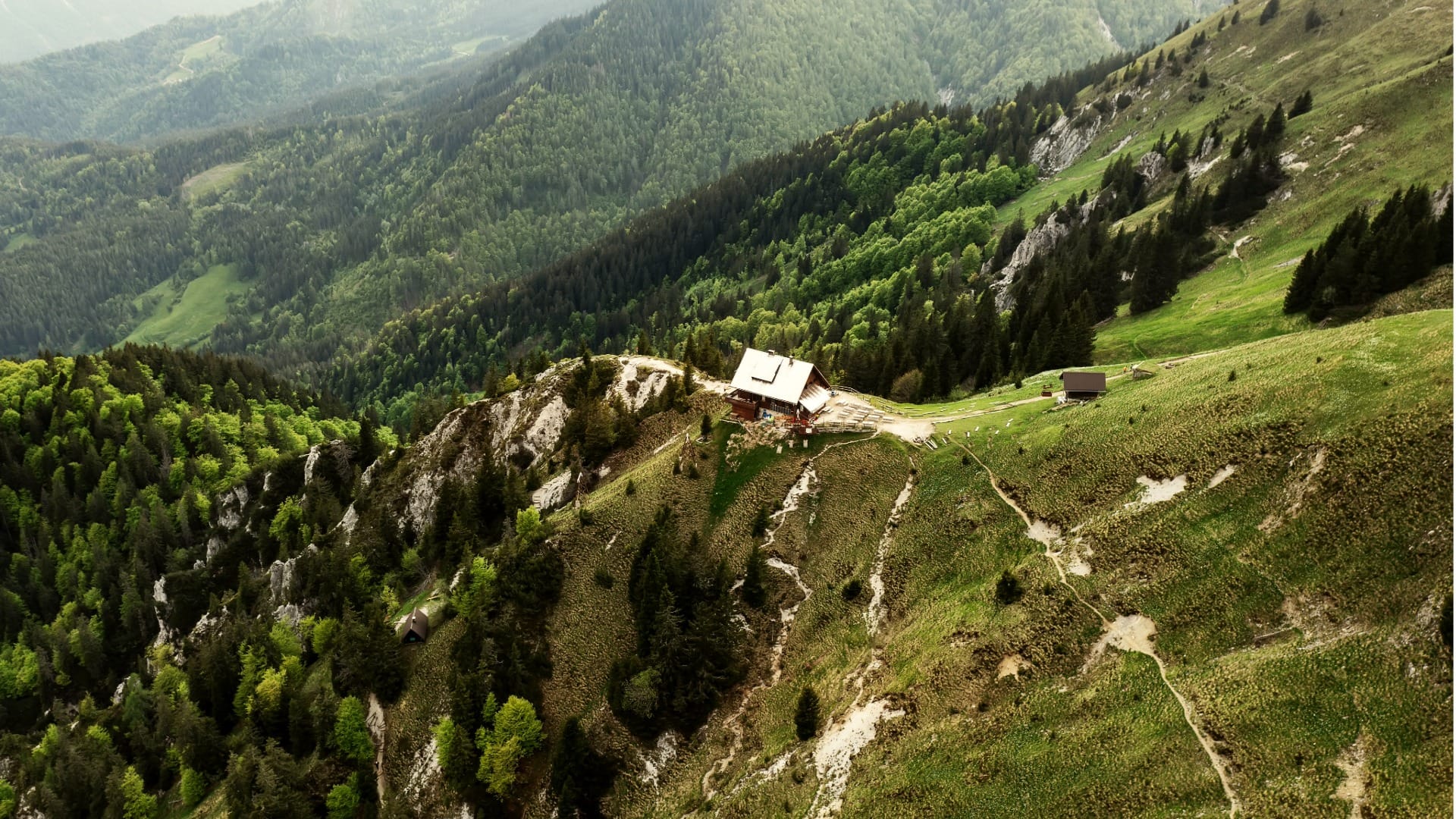 Aerial view of the Koča na Golici mountain hut on the forested ridge below the Golica summit