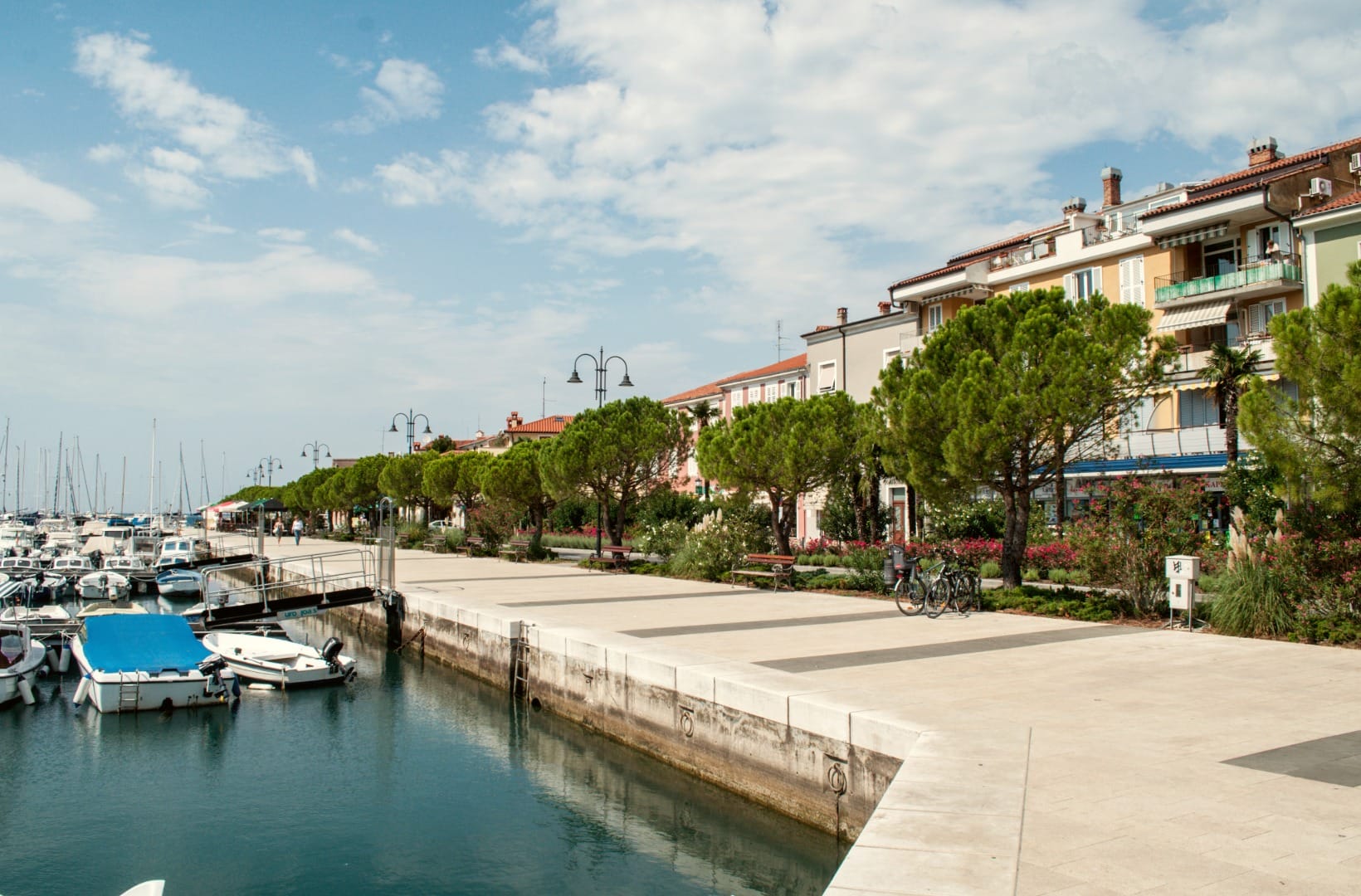Izola waterfront with fishing boats moored along a stone quay and pastel townhouses behind