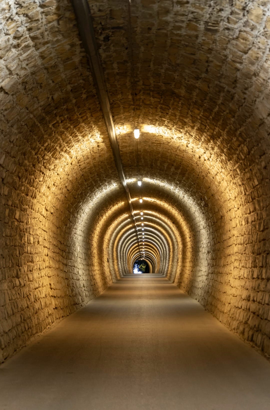 Interior of the brick-lined Valeta railway tunnel on the Parenzana, lit by a row of lamps along the crown