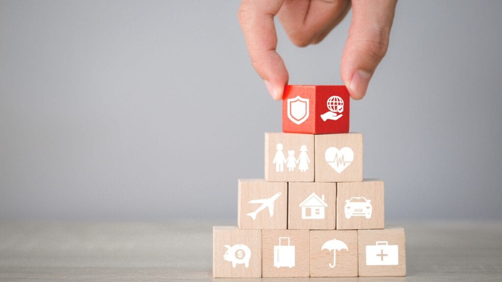 Wooden blocks with icons for travel, health, home and family insurance