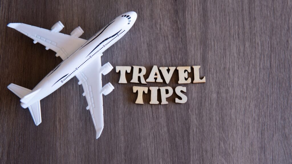 Toy airplane next to wooden letters spelling travel tips