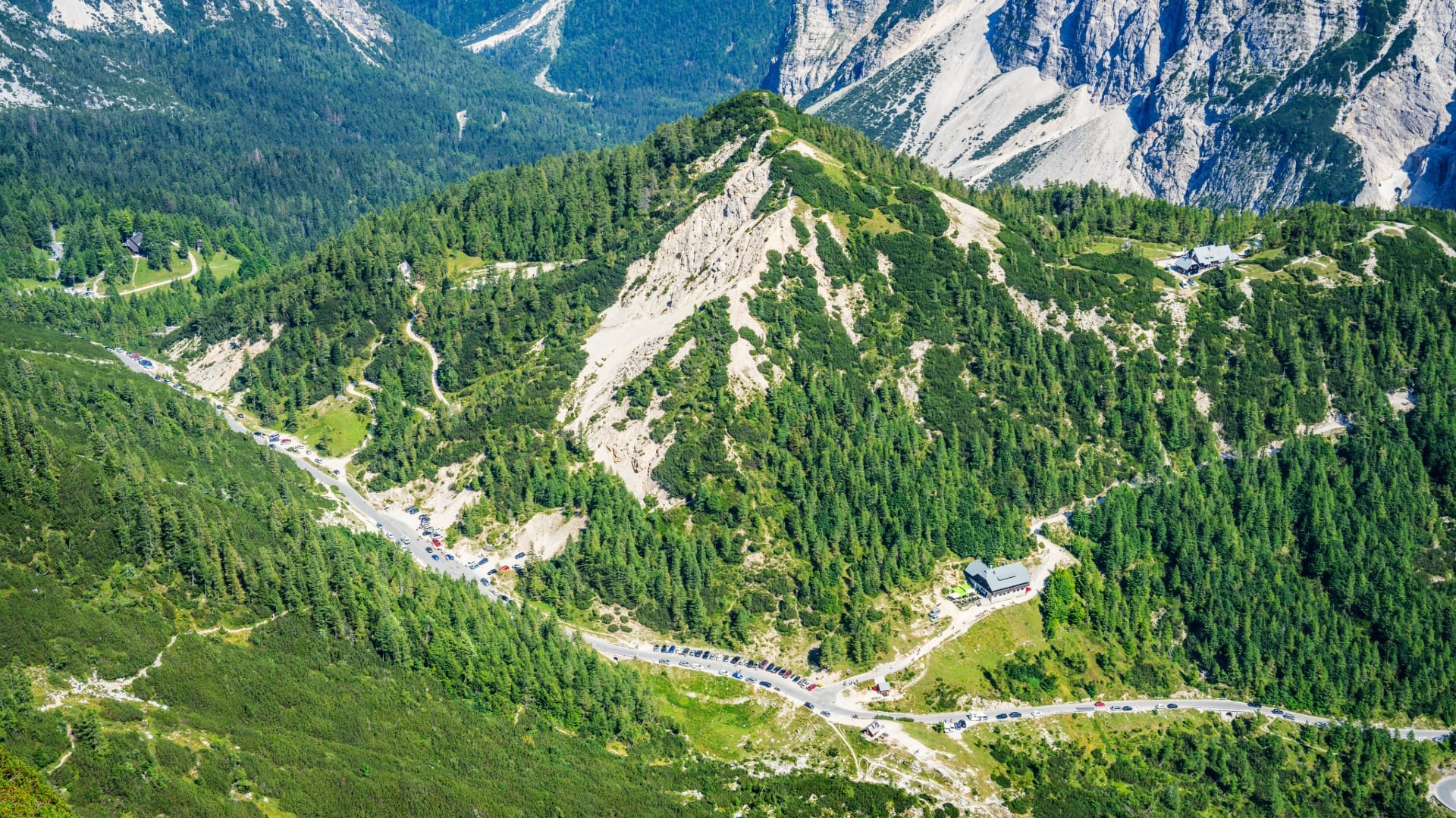 Aerial view of Vršič Pass with its switchback road, parking area and mountain hut
