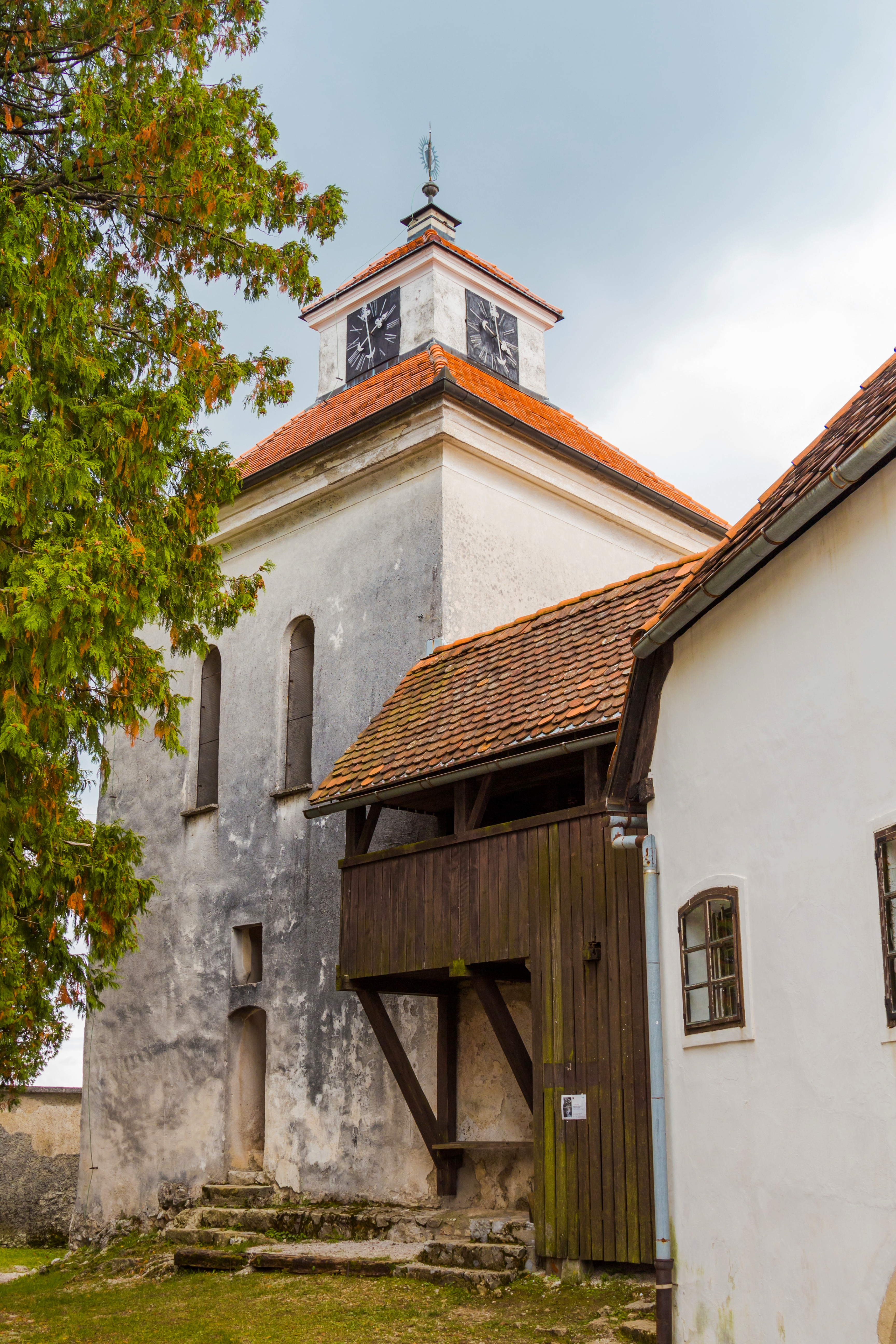 Campanario de la iglesia en la cima de Šmarna Gora con esferas de reloj y tejado de tejas rojas