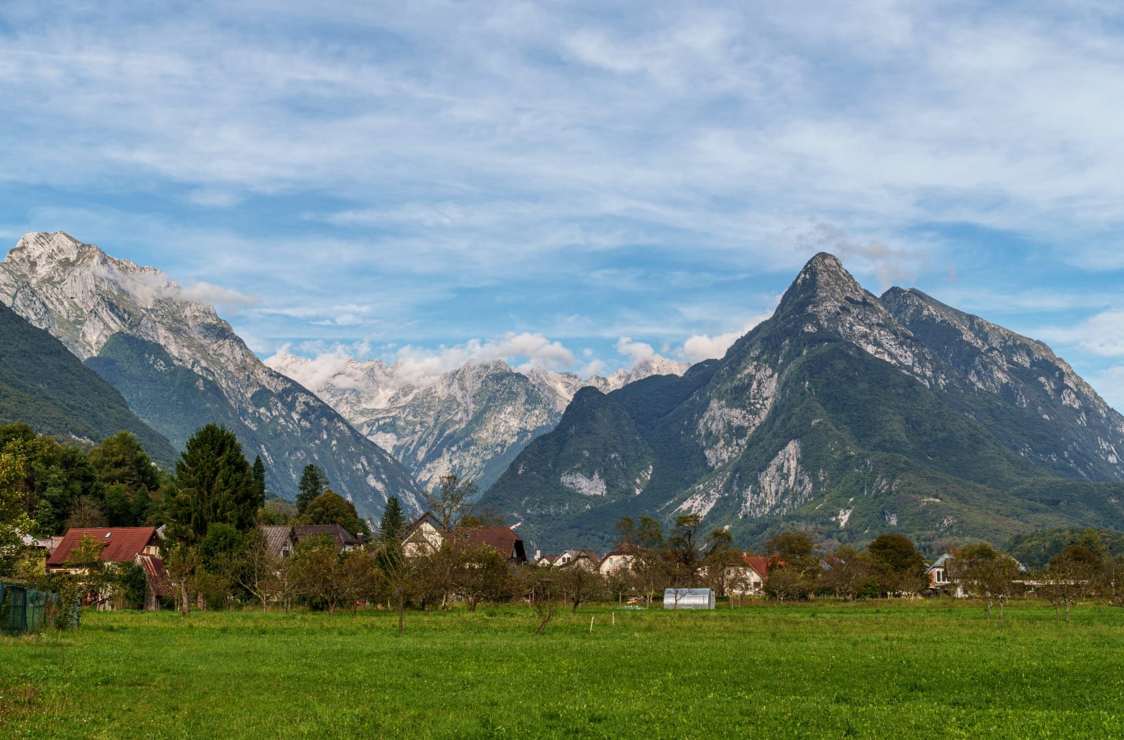 The Bovec basin with the pyramid peak of Svinjak and the Julian Alps rising behind green meadows