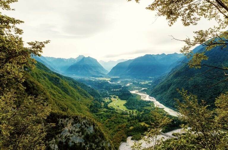 The braided Soča river winding through the green valley floor below the Julian Alps, seen from a viewpoint above