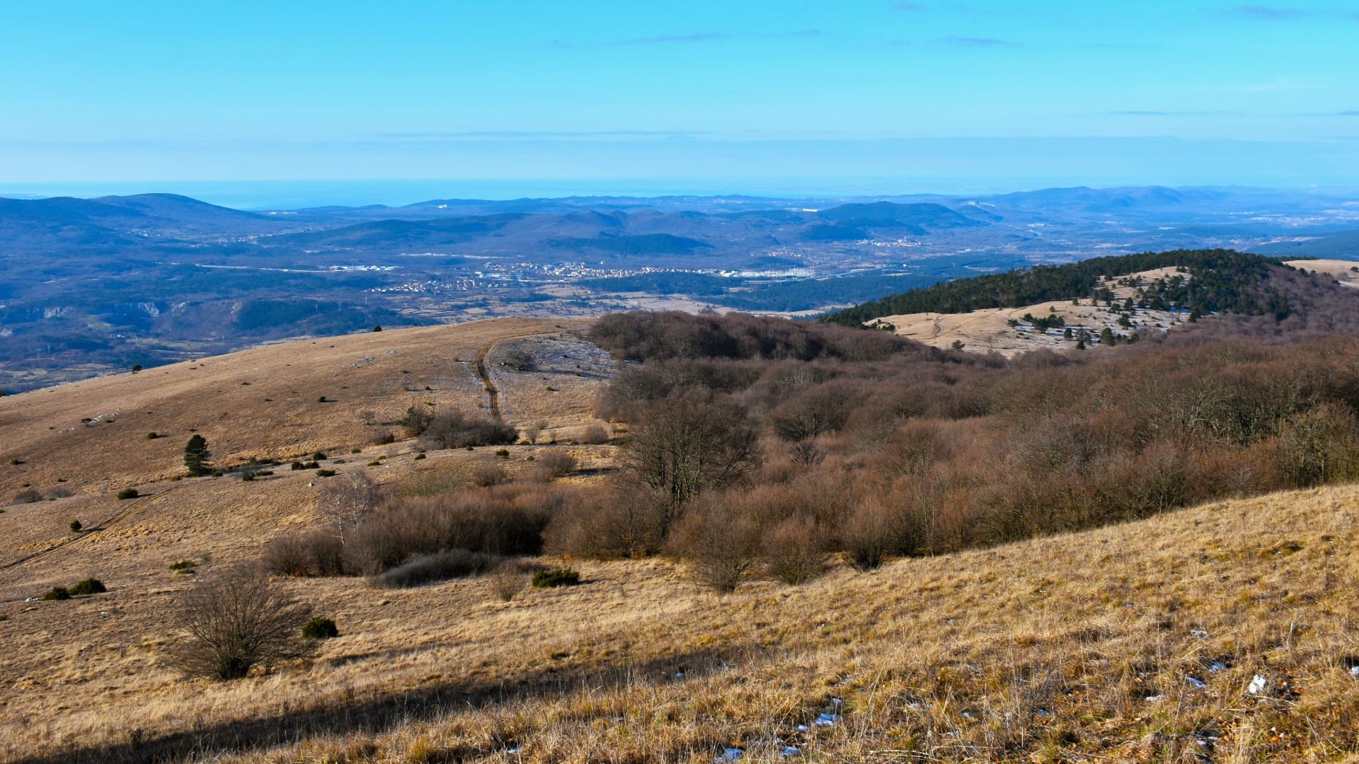 Open ridge path on Vremščica with a hazy view toward the Adriatic coast