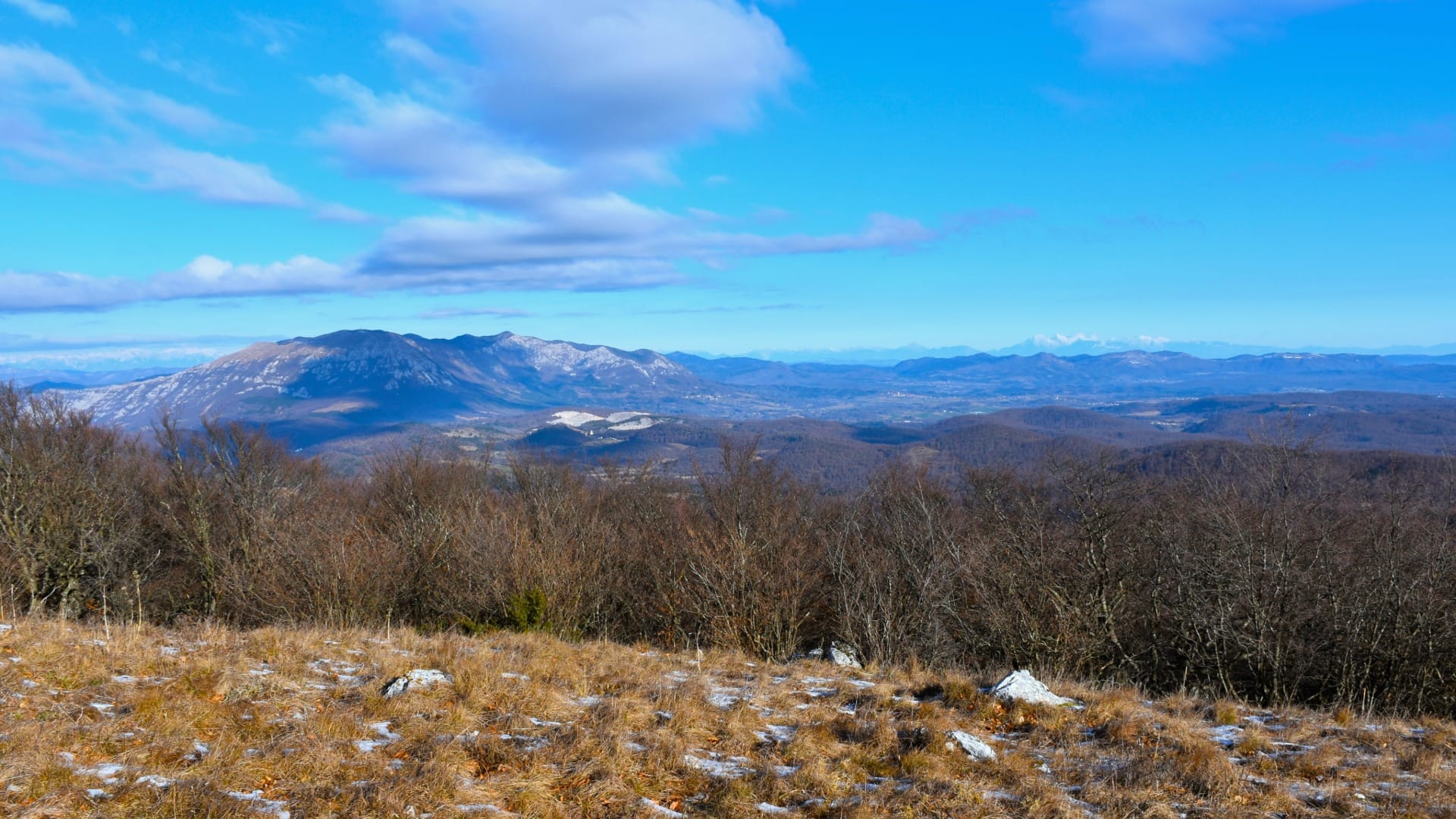 Grassy summit ridge of Vremščica with snow-capped Julian Alps on the horizon